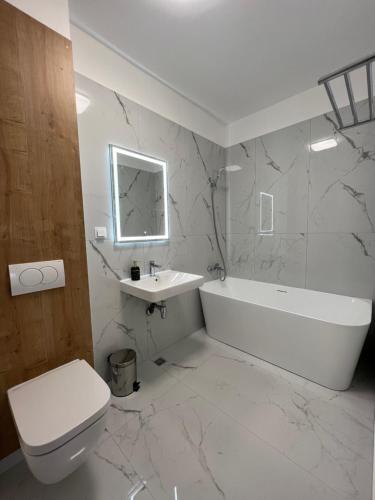 Baño blanco con bañera blanca y lavamanos en Exit Aparthotel, en Floreşti