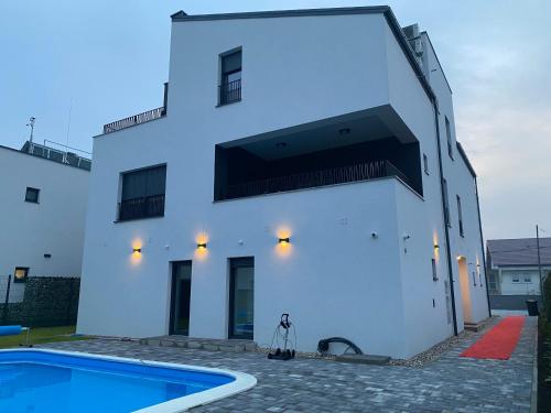- un bâtiment blanc avec une piscine en face dans l'établissement 4TREES Airport Apartments, à Velika Gorica