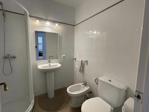 a white bathroom with a toilet and a sink at Sa Posta in Cala en Forcat