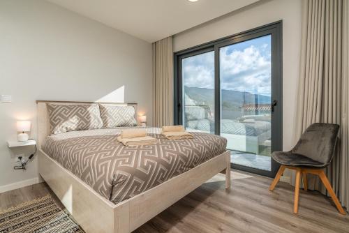 a bedroom with a bed and a chair and a window at Casa Barros Serra in Calheta