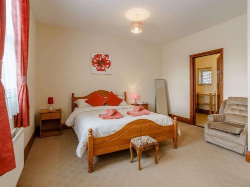 Un dormitorio con una cama con almohadas rosas y una silla en 3 Bed in Nantgaredig 56410 en Llanfynydd
