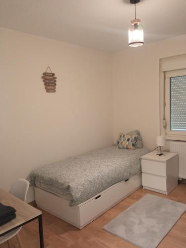 a bedroom with a bed and a table and a window at Chez François: appartement 3 chambres 4 personnes in Saint-Avold