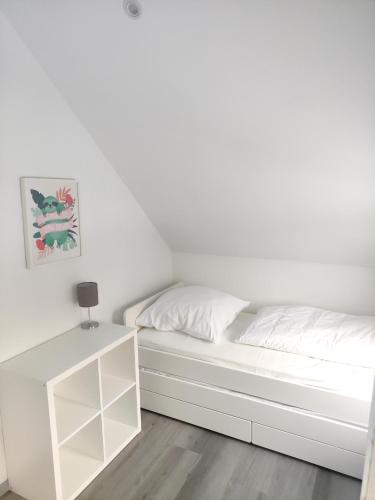 a white bed in a white room with a table at Ferienhaus Sophia 70qm bis 5 Gäste mit Fass-Sauna, Whirlpool April bis Oktober, 75qm Terrasse und eingezäunten Garten in Sierosław