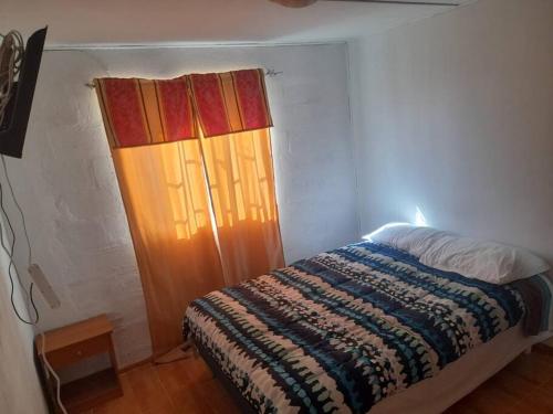 a bedroom with a bed and a window with a blanket at arriendo casa para 6 personas in Caldera