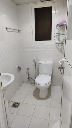 La salle de bains blanche est pourvue de toilettes et d'un lavabo. dans l'établissement Al Khaleez Accommodation, à Dubaï