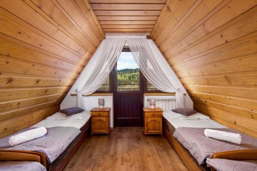 two beds in a wooden room with a window at Dom Wypoczynkowy GALICA in Poronin