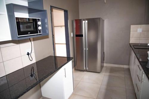 uma cozinha com um frigorífico de aço inoxidável e um micro-ondas em Feel Home em Pretoria