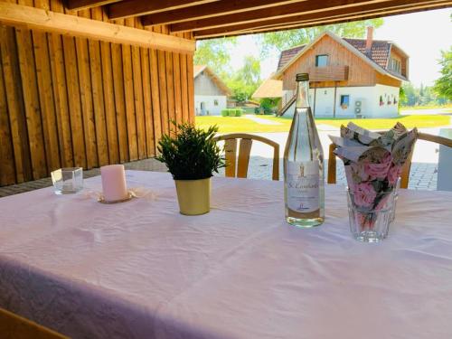 Ferienwohnung in Aistersheim : زجاجة من النبيذ و إناء من الزهور على طاولة