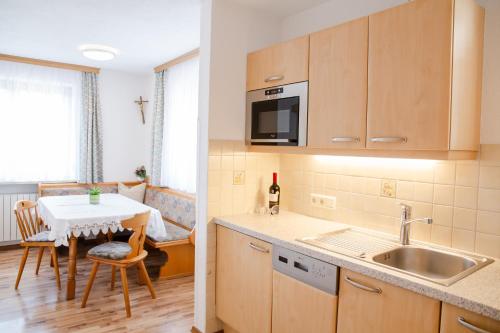 a kitchen with a sink and a table with a chair at Haus Stecher in Nauders