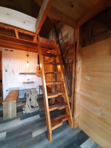 um sótão com uma escada de madeira num quarto em Tiny House Conguillio em Melipeuco