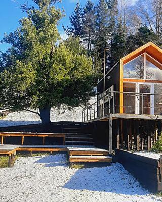 a building with stairs and a tree in front of it at Tiny House Conguillio in Melipeuco