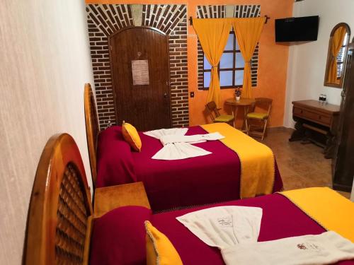 ein Hotelzimmer mit 2 Betten und einem Tisch in der Unterkunft Hotel El Aguila in Villa del Carbón