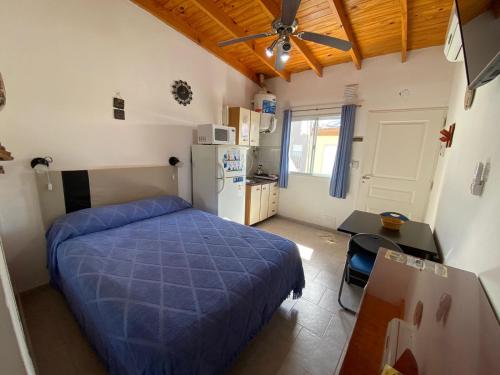 a bedroom with a bed and a table and a refrigerator at Alquileres "Agus" in Las Grutas