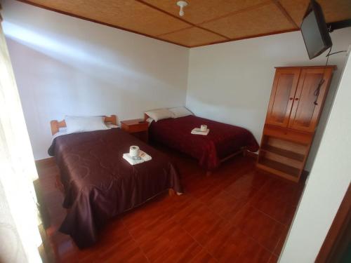 a small room with two beds and a cabinet at Hospedaje Pinky Lodge in Oxapampa