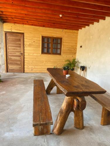 une table et un banc en bois devant un bâtiment dans l'établissement Hospedaje El Tucan, à Puerto Iguazú