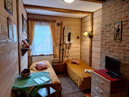 um pequeno quarto com 2 camas e uma televisão em Dom Gościnny Dudek em Krynica Zdrój