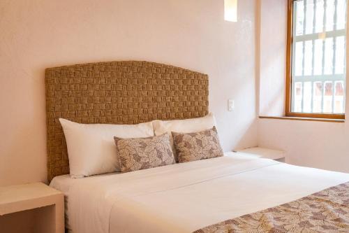 1 dormitorio con cama blanca y cabecero grande en Casa Noa Colonial Rooms By SOHO, en Cartagena de Indias