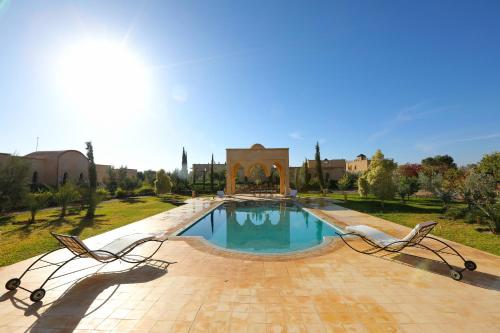 a swimming pool in a park with two chairs at Atlas Widan in Marrakesh