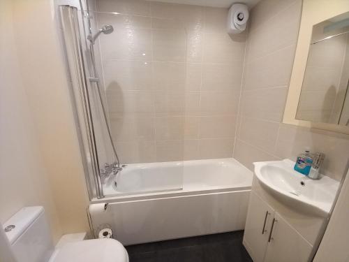 a bathroom with a tub and a toilet and a sink at Modern large 2 Bed whole apartment - Free parking - Ground floor - Central Beeston in Nottingham