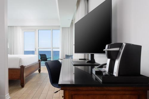 a hotel room with a bed and a desk with a television at The Pensacola Beach Resort in Pensacola Beach