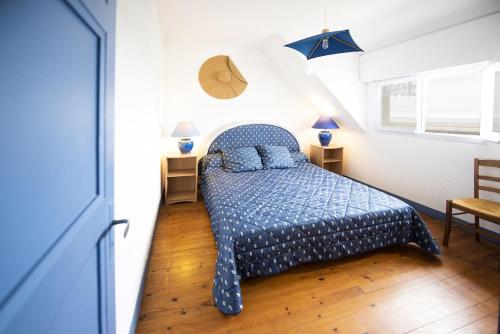 a bedroom with a bed with a blue comforter at Villa Quiné Plage in Quinéville