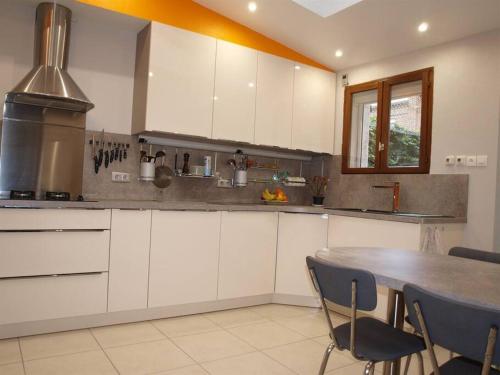 a kitchen with white cabinets and a table and chairs at Charming City Home Near Downtown with Garage in Amiens