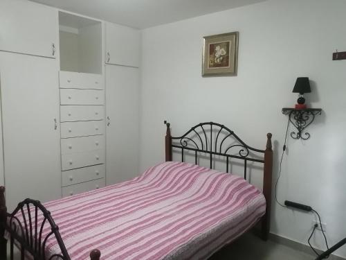 - une chambre avec un lit et une couverture rayée rose dans l'établissement Cerca del aeropuerto HABITACIÓN INDEPENDIENTE CON BAÑO PRIVADO Área muy tranquila entre chanis y costa del este, à Panama City