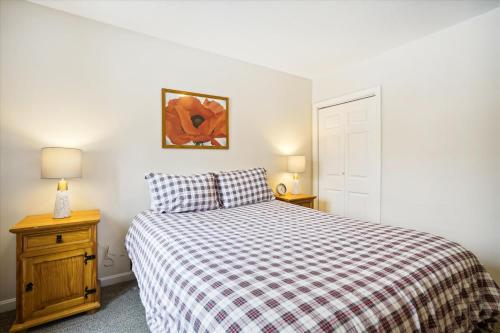 a bedroom with a bed with a plaid comforter and two lamps at Cozy 2-Bedroom Northbrook #3 with Fireplace in Killington