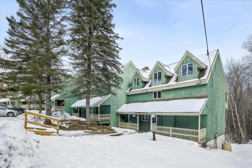 a green house with snow in front of it at Cozy 2-Bedroom Northbrook #3 with Fireplace in Killington