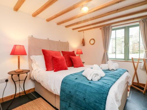 a bedroom with a large bed with red pillows at Hay Loft in Camborne