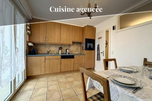 a kitchen with wooden cabinets and a dining table at Plein Ciel Horizon I Balcony I Near cable cars I Parking I View of the Alps in Crans-Montana