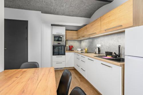 una cucina con armadi bianchi e tavolo in legno di Apartmán Hamrovka a Velké Hamry