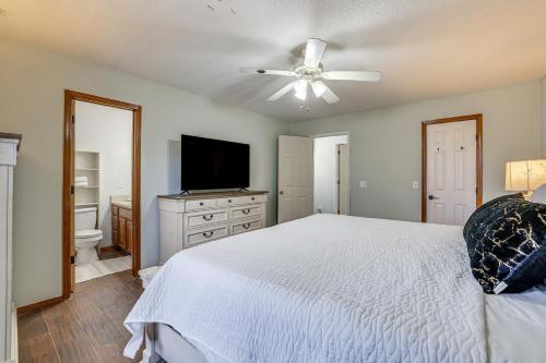 a bedroom with a white bed and a flat screen tv at Rogers Vacation Home with Yard 5 Mi to Bentonville in Rogers