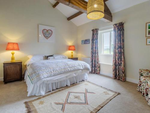 a bedroom with a bed and two lamps and a window at Ivy Cottage - Uk42246 in Broughton