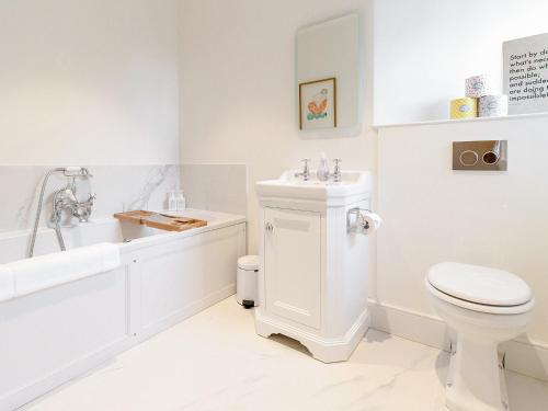 a white bathroom with a toilet and a tub and a sink at The Manse - Uk42249 in Broughton