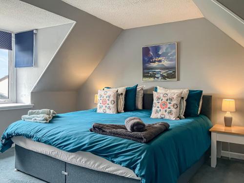 a bedroom with a bed with blue sheets and pillows at Beach Croft in Brora