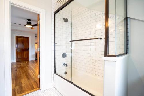 a glass shower in a white bathroom with a wooden floor at Smiths Crescendo in Denver