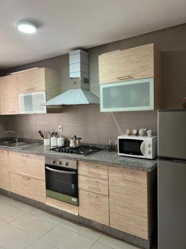 a kitchen with wooden cabinets and a microwave oven at Luxury Apartement Near the Beach in Sidi Bouqnadel