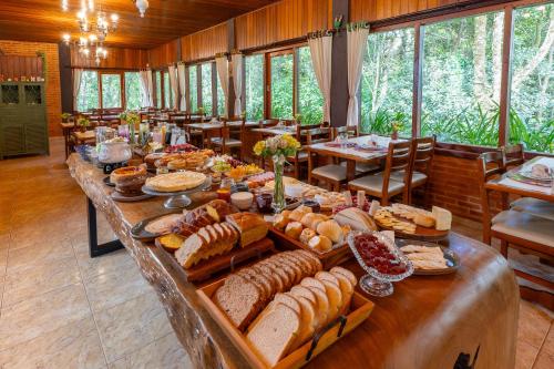 una larga mesa llena de muchos tipos diferentes de pan en Pousada Cerejeiras, en Monte Verde