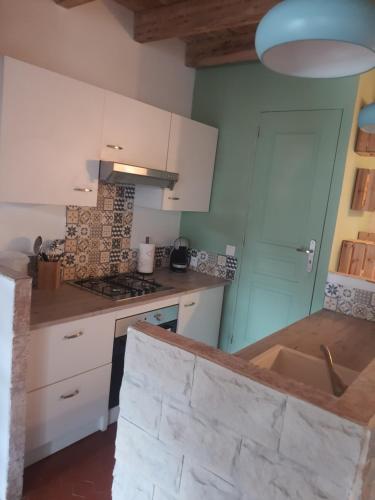 une cuisine avec des armoires blanches et un comptoir dans l'établissement Maison Isola Village, à Isola