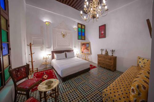 a bedroom with a bed and a couch and a chandelier at Riad Soultan in Fès