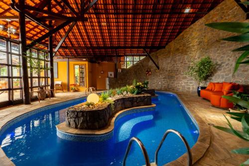 a swimming pool in a house with a log in the middle at Pousada Cerejeiras in Monte Verde