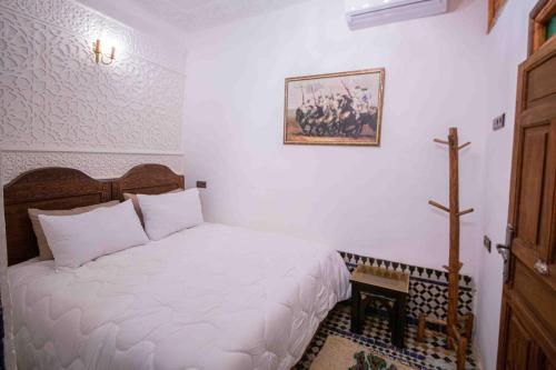 a bedroom with a white bed and a cross on the wall at Riad Soultan in Fès