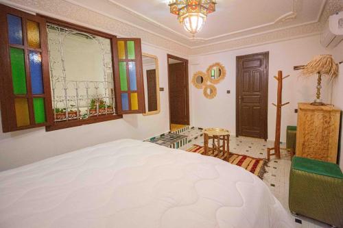 a bedroom with a white bed and a colorful window at Riad Soultan in Fès