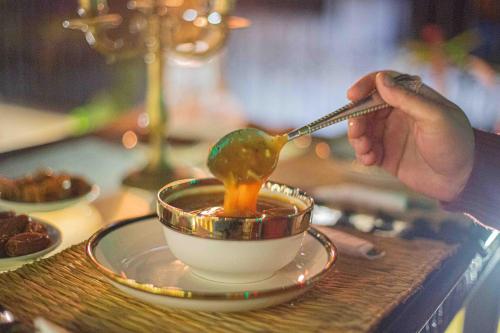a person stirring a bowl of soup with a spoon at Riad Soultan in Fès