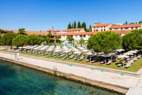 a row of lawn chairs in front of a large body of water at Hotel Histrion in Portorož
