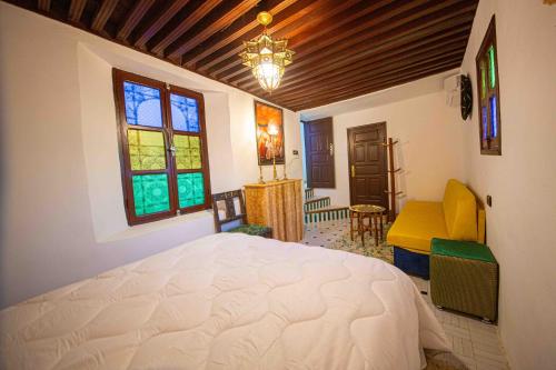 a bedroom with a white bed and a chandelier at Riad Soultan in Fès