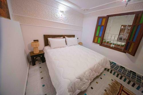 a bedroom with a white bed with a window at Riad Soultan in Fès