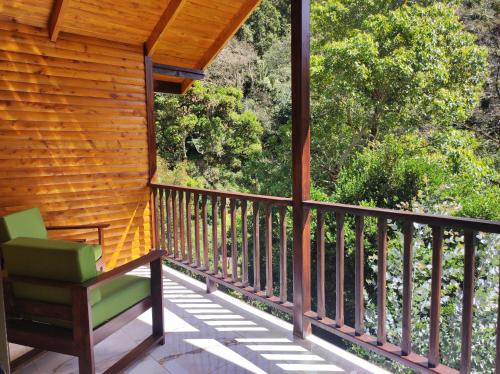 a porch with a green chair on it at Cabinas El Quetzal in San Gerardo de Dota