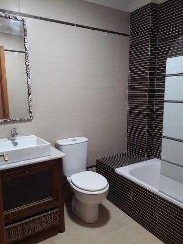 y baño con aseo, lavabo y bañera. en Apartamento Playa Cárabos en Melilla